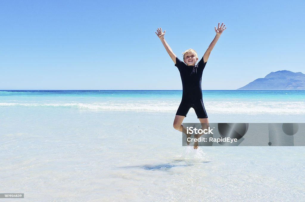 Enérgico 10 años viejo niño saltos de alegría en la playa - Foto de stock de Niño libre de derechos