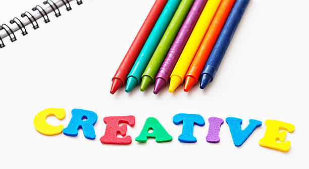 istock Toy letters spell CREATIVE by multi-colored crayons on sketchbook 181955513