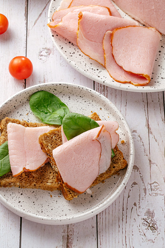 ham sandwich on a white plate on a wooden table in Paris, Île-de-France, France