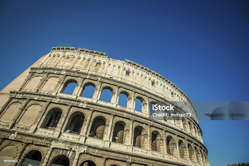 Colosseum in Rome The photo was composed in order to have the bright sun in coming out from the edge. A prime lens at f8 was used to have the perfect star shape coming from the sun. Amphitheater Stock Photo