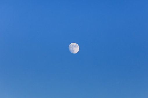 Full moon floating in the blue sky.