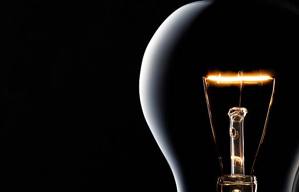 Light Bulb on black. Light bulb is on in front of black backgrounds. light bulb filament photos stock pictures, royalty-free photos & images