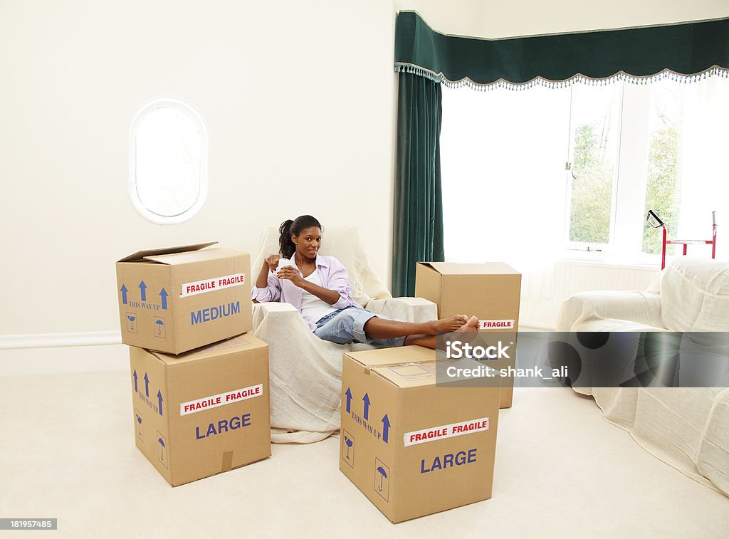 mature female moving house A mature women taking a coffee break while packing boxes during moving house. Moving House Stock Photo
