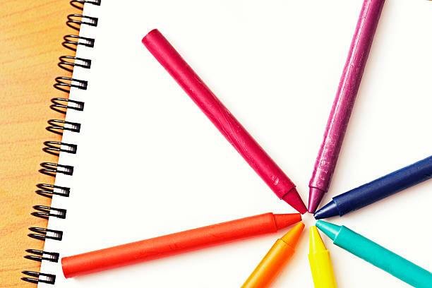 istock Wheel of rainbow-colored wax crayons on blank sketchbook 181957652