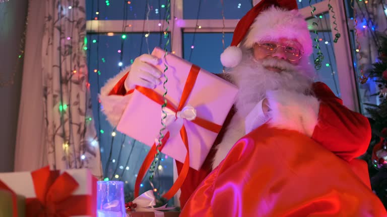 Santa takes out a large box of gifts tied with a red ribbon and puts it in present bag to give at the Christmas party