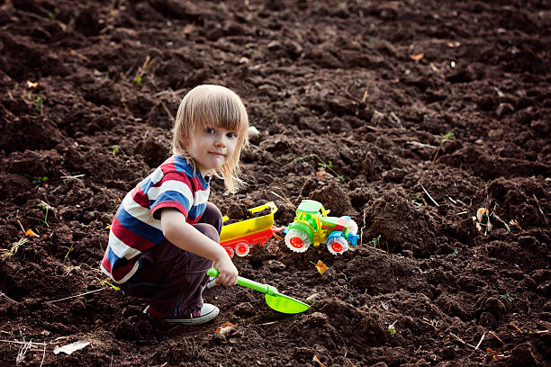 istock Little boy playing with a toy tractor 181958689