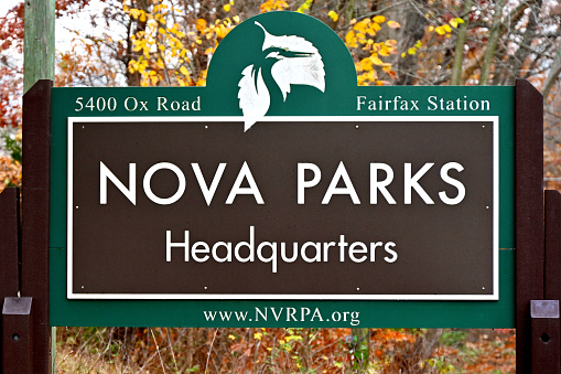 Fairfax Station, Virginia USA - November 18, 2023: Sign at the entrance to the NOVA Parks Headquarters building surrounded by colorful autumn leaves.