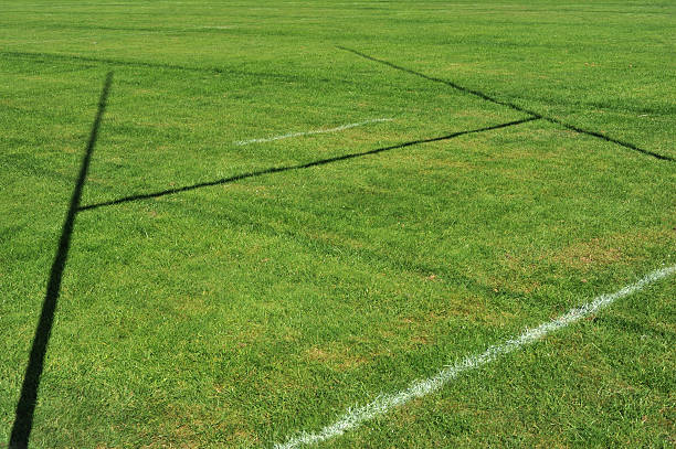 Green grass of a rugby field with shadow of a goalpost stock photo
