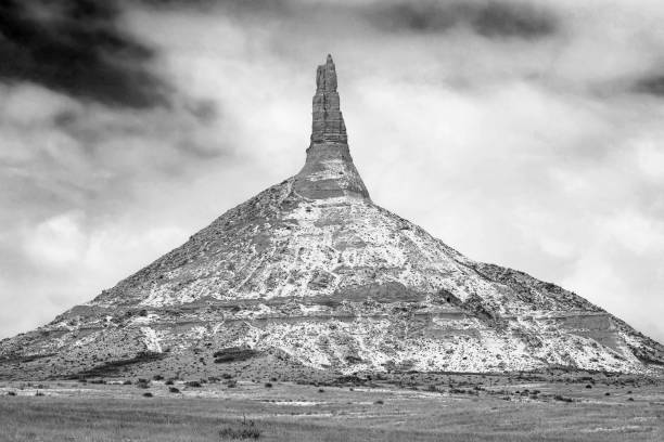 classic black and white retro image of snow-dusted Chimney Rocky during winter in the high arid prairie of Nebraska a landmark along the old Oregon Trail