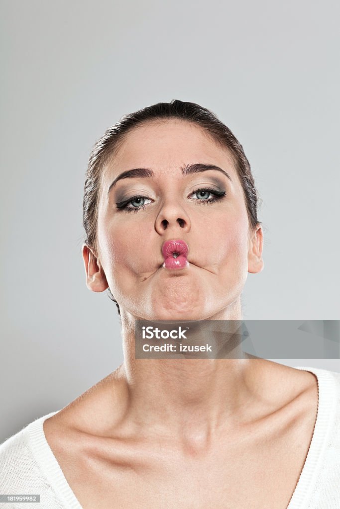Woman making a face Portrait of  young woman making a silly face. Studio shot, grey background. 20-24 Years Stock Photo