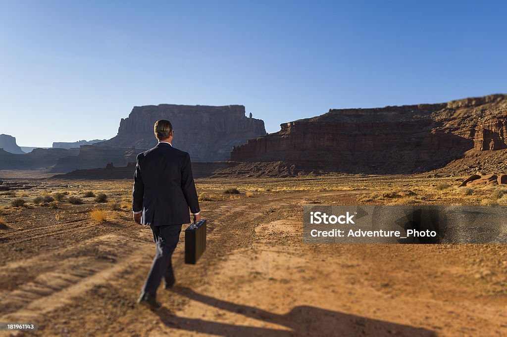 Homme d'affaires dans le désert aride à quelques minutes avec porte-documents - Photo de Admirer le paysage libre de droits