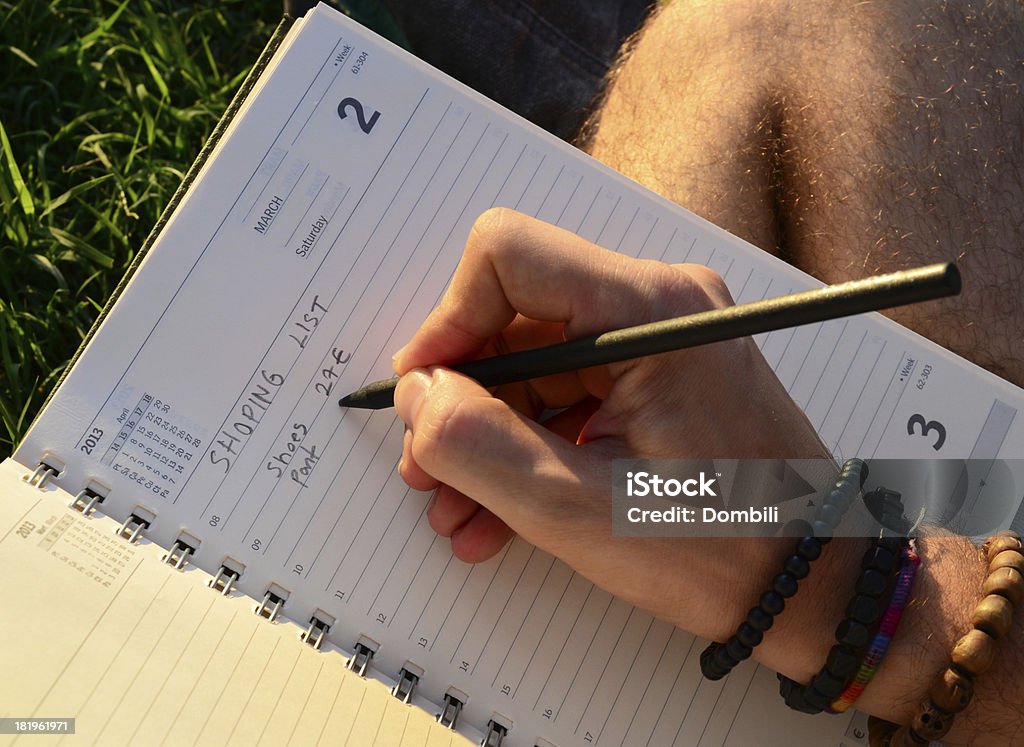 Young Man Writing On The Grass Writing on a sunny garden in a warm and pleasant atmosfere Book Stock Photo