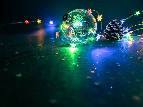 glass ball with snowflakes illuminated by colorful light of christmas garland.