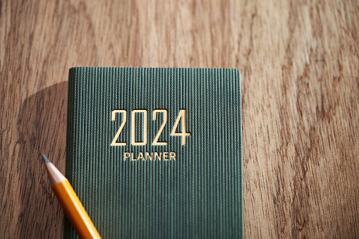 2024 planner and yellow pencil on wood background