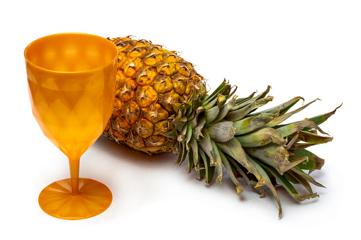Ripe pineapple with a cup on a white background