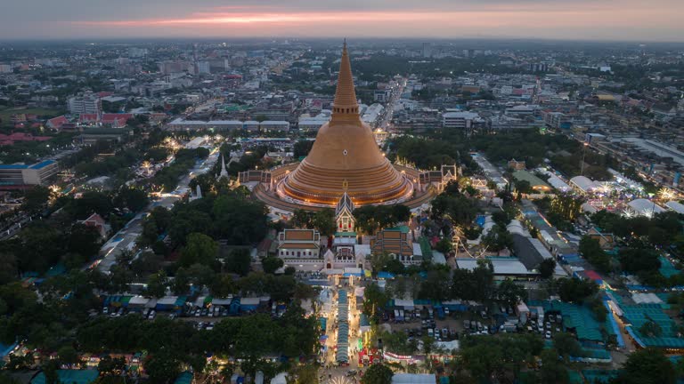 Hyper lapse or Drone lapse aerial view of Phra Pathommachedi at sunset during temple fair or night market festival, The great golden pagoda and world's tallest stupa in Nakhon Pathom province, western side of BangkokThailand