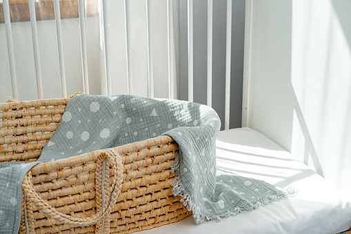Nursery interior and bedding for kids with wicker bassinet close up