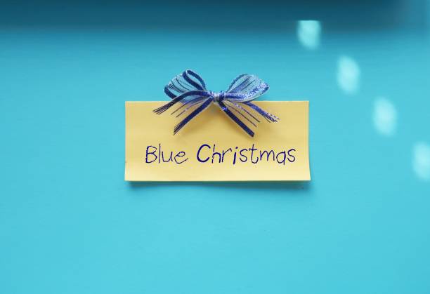 istock Yellow note on blue background with handwritten text Blue Christmas -  means sadness in festive time, away from family- feelings of loneliness, money worries, family tensions, relationship troubles, social anxieties or peer expectations 1819801539