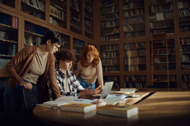 istock Group of high school students using laptop in library. 1819812272