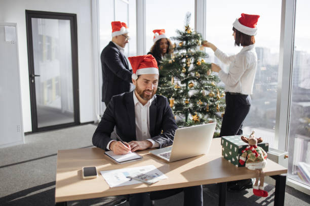 istock Young businessman in a Santa hat with pen making notes on draft of paper document 1819812663