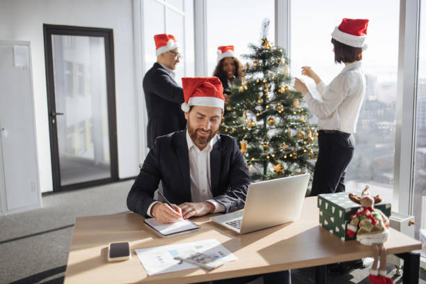 istock Young businessman in a Santa hat with pen making notes on draft of paper document 1819812671