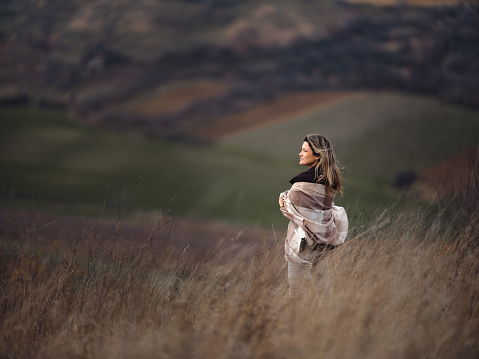Back view of young woman day dreaming while standing on a hill in autumn day. Photographed in medium format. Copy space.