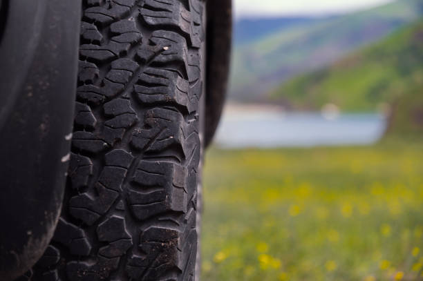 Transport, driving and car concept, close-up of a car wheel on green lush grass. A car wheel stands in the mountains in summer stock photo