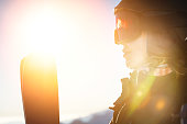 Ski portrait of a woman in a helmet, cool ski goggles on a cold sunny day. A smiling girl in profile stands in the mountains and looks at the beautiful views