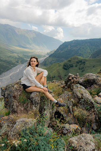 Serene woman sitting on rock overlooking valley in   mountains