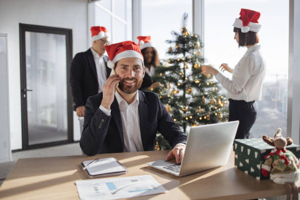 istock Businessman in Santa hat talking on smartphone and looking at camera 1819858417