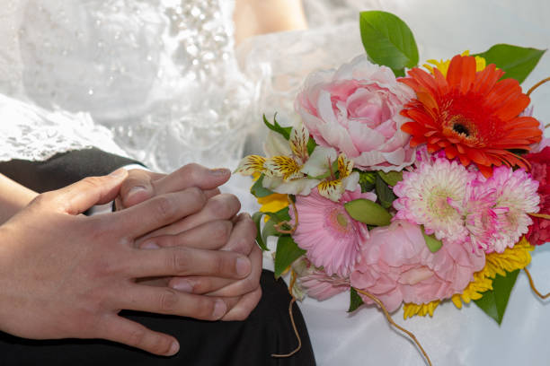istock A pair clasping hands while holding a bouquet of flowers 1819868545