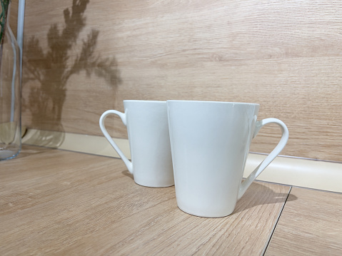 Two coffee cups on a wooden table in a coffee shop, stock photo.