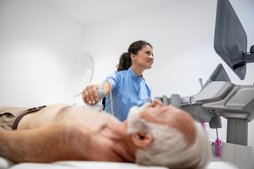 Female doctor examining internal organs with ultrasound equipment in hospital.