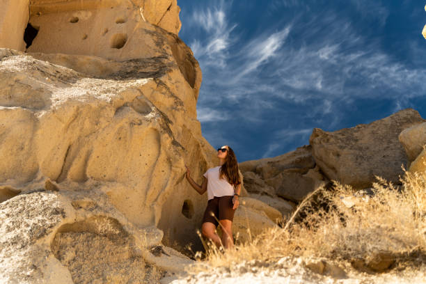 istock A young woman examines ancient structures in the rocks against the backdrop of wispy clouds in the blue sky. 1819933471