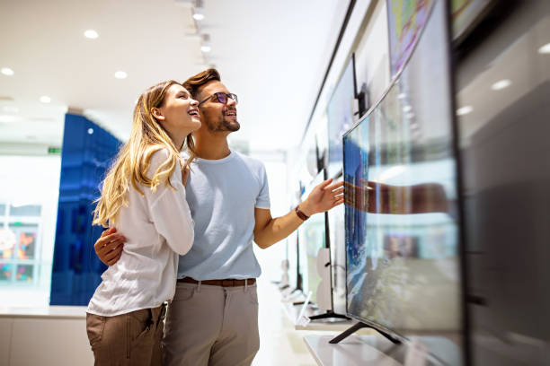 istock Young couple in consumer electronics store looking at latest digital devices, television. 1819937198