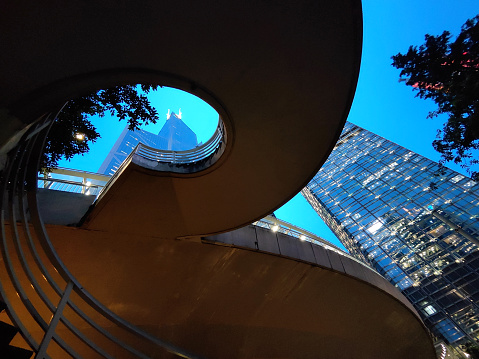 Spiral staircase under the Cheung Kong Centre and Bank of China Tower at dusk in Hong Kong Admiralty district.
