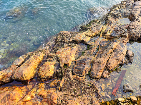 Rocky shore at Deep Water Bay. The bay is located on the southern shore of Hong Kong Island in Hong Kong. The bay is surrounded by Shouson Hill, Brick Hill, Violet Hill and Middle Island.