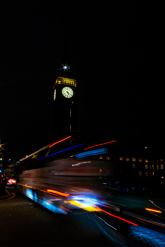 Traffic in London at night. Long exposure image with light trails from buses and cars beside Big Ben in Westminster, London, UK.