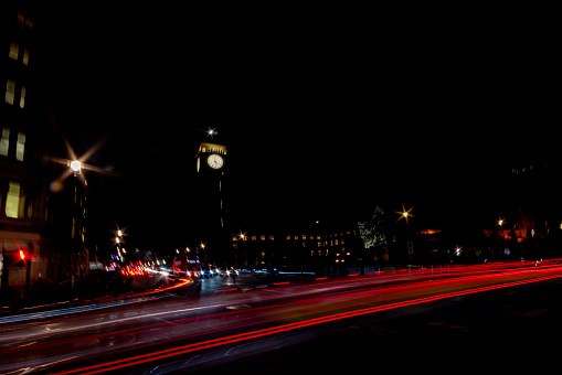 Traffic in London at night. Long exposure image with light trails from buses and cars beside Big Ben in Westminster, London, UK.