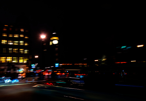 Traffic in London at night. Long exposure image with light trails from buses and cars beside Big Ben in Westminster, London, UK.  This is a deliberate blur using in camera movement (ICM) to create an abstract effect.