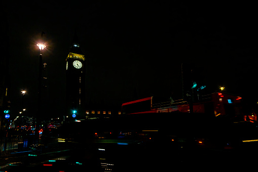 Traffic in London at night. Long exposure image with light trails from buses and cars beside Big Ben in Westminster, London, UK.