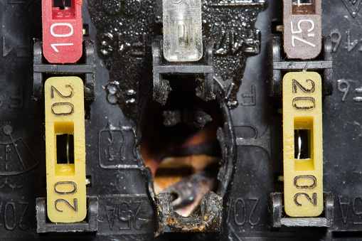 Burnt out car fuse box. Defective fuse block. Close-up photo.