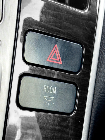 A detailed view capturing the hazard lights button in the interior of a car, highlighting its location and design amidst the dashboard features.