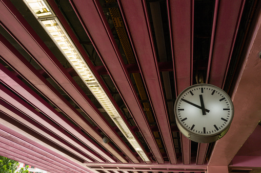 Clock hanging down in the pink train station in Singapore