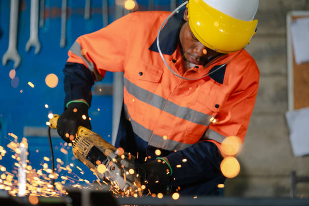 un ouvrier africain utilise une scie circulaire pour façonner l’acier. l’industrie prend vie dans une symphonie d’étincelles et de machines. - outillage électrique photos et images de collection