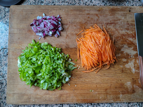 Chopped onions, carrots and peppers on cutting board