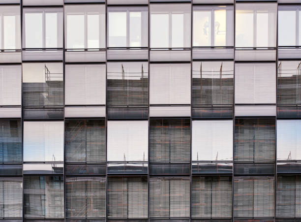 Front view pattern of windows or glazed casement on a modern building with lowered blinders or curtains to stop the sun. Glazed fenestra or fanlights shine against the sun with closed jalousie - Friedrichstadt, Berlin, Germany patrón de vista frontal de ventanas o ventanas acristaladas en un edificio moderno con anteojeras o cortinas bajadas para detener el sol. la fenestra vidriada o los lucernarios brillan contra el sol con celosía cerrada - friedrichstadt, berlín, alemania