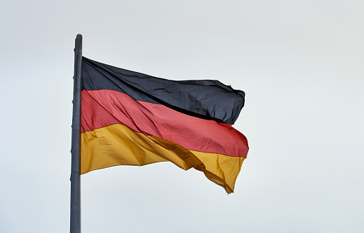 Closeup of a big German flag fluttering on a pole. Flying German or Deutschland flag detail or closeup view - Berlin, Germany