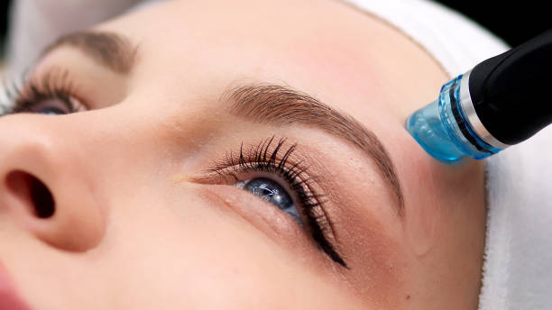 istock Professional dermatologist in medical gloves doing hydro peeling procedure for beautiful woman patient in cosmetology clinic. Close up facial treatment. 1820029632