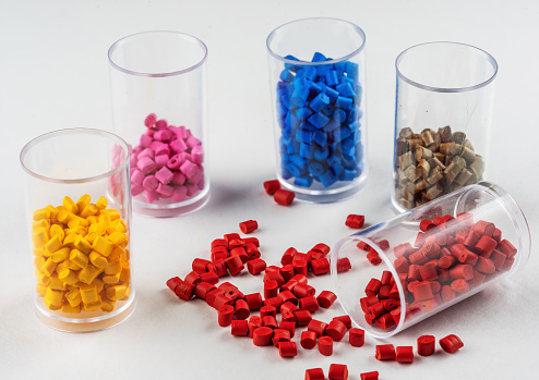 multi-colored plastic dye in granules in test tubes isolated on a white background. flasks with colored dye in granules for plastics. polymer industry